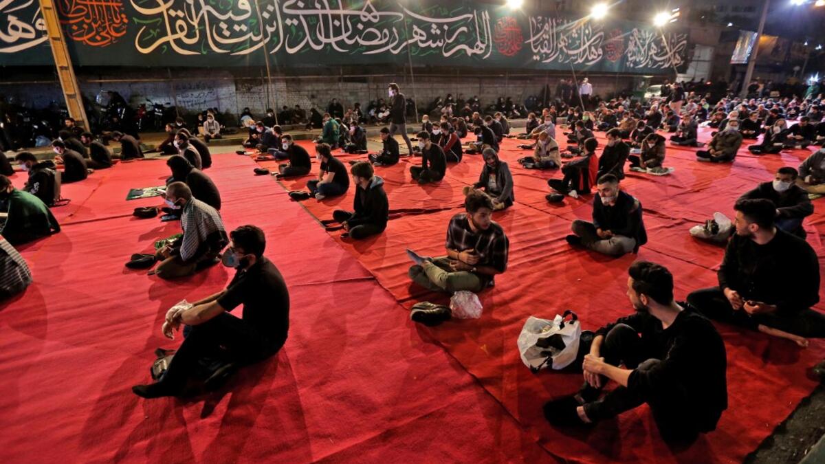 Iranians wearing face masks against the Covid-19 coronavirus attend Laylat al-Qadr prayers, one of the holiest nights during the Muslim fasting month of Ramadan, outside a mosque in the Tehran, on May 13, 2020. ATTA KENARE / AFP