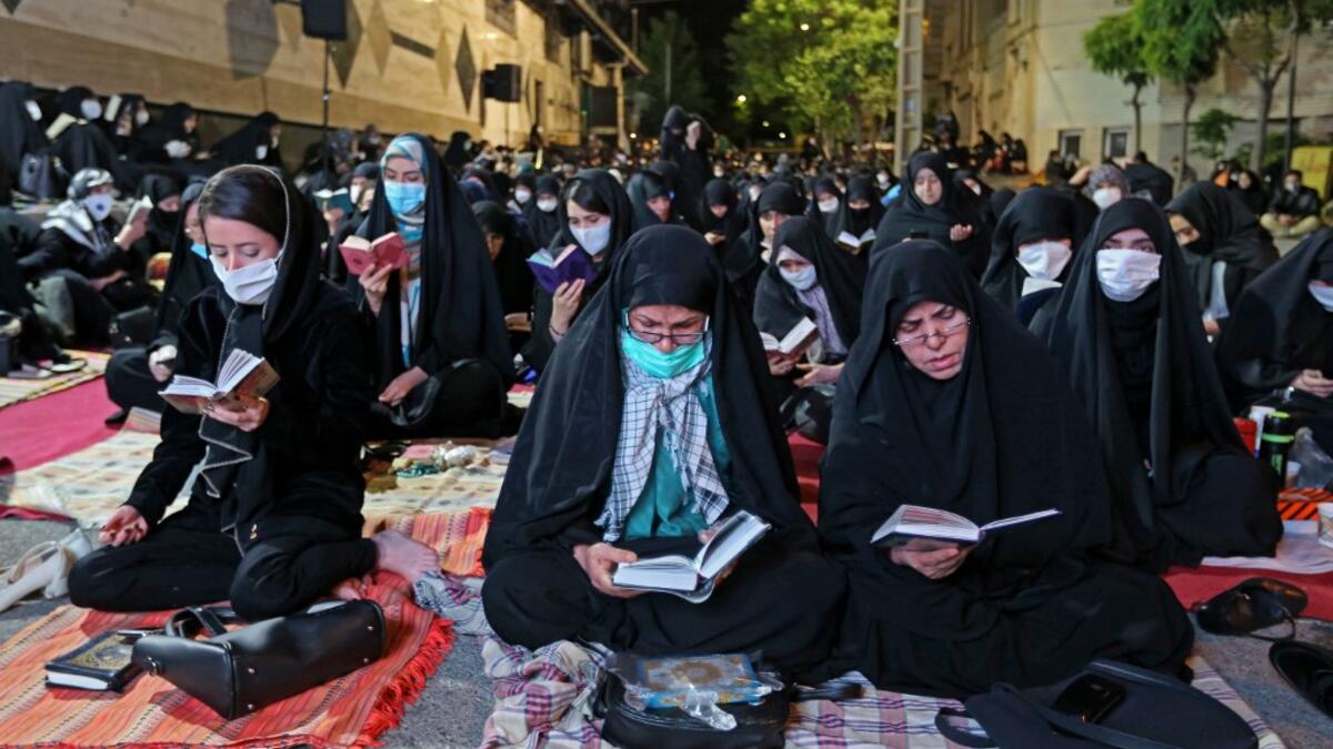 Iranians wearing face masks against the Covid-19 coronavirus attend Laylat al-Qadr prayers, one of the holiest nights during the Muslim fasting month of Ramadan, outside a mosque in the Tehran, on May 13, 2020. ATTA KENARE / AFP