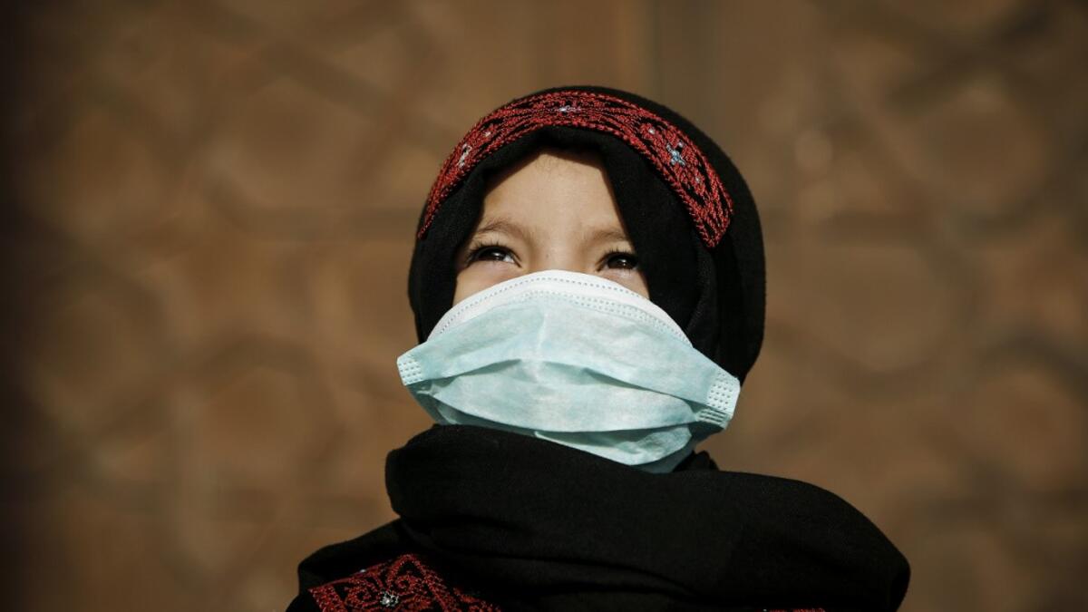 A Palestinian child clad in mask due to the COVID-19 coronavirus pandemic stands outside a mosque upon arriving for the prayers of Eid al-Fitr, the Muslim holiday which starts at the conclusion of the holy fasting month of Ramadan, in Gaza City on May 24, 2020. Local authorities in the Hamas-run Palestinian enclave allowed mosques to reopen for Eid al-Fitr as social distancing procedures for the novel coronavirus are maintained while encouraging the elderly to perform prayers from home. MOHAMMED ABED / AFP