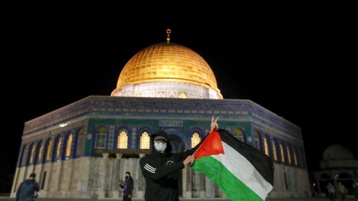 A Palestinian youth waves a national flag in front of the Dome of Rock at the Al-Aqsa Mosque compound, before the start of the dawn prayer (salat al-fajr) inside the compound in Jerusalem's Old City, on May 31, 2020, after a two-month closure due to the COVID-19 pandemic. AHMAD GHARABLI / AFP