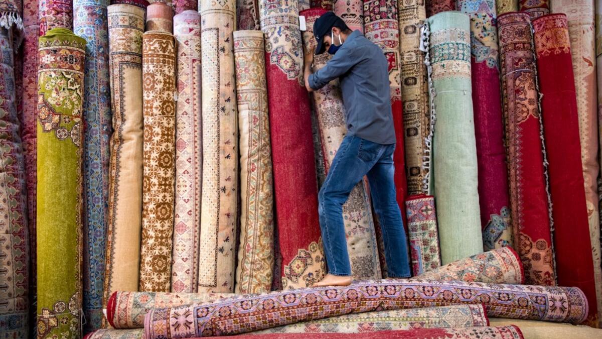 A Moroccan rug dealer lines up carpets at a shop in the city of Sale, north of the capital Rabat, on June 3, 2020, during the novel coronavirus pandemic. Artisans in Morocco have been starved of income for almost three months because of the COVID-19 pandemic. The crafts industry represents some seven percent of GDP, with an export turnover last year of nearly 1 billion dirhams ($100 million). FADEL SENNA / AFP