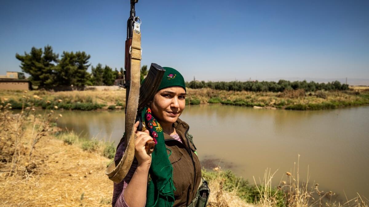 A Kurdish female volunteer, from the newly formed Community Protection Forces, guards a wheat field, against threats by jihadists to burn the crops, during harvest season on June 13, 2020, in the countryside east of Qamishli in Syria's northeastern Hasakah province. Delil SOULEIMAN / AFP