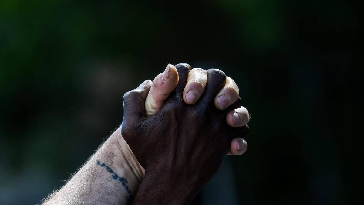 Micheal Jones (R) holds hands with Tim Higgins (L) as they protest on the fourth day on the fourth day following Rayshard Brooks' shooting death by police in a Wendy's restaurant parking lot, June 16, 2020, in Atlanta, Georgia. The fatal shooting of Brooks, a black man, by a white police officer in Atlanta has poured more fuel on the raging US debate over racism, prompting another round of street protests and the resignation of the southern city's police chief. The death of 27-year-old Rayshard Brooks was r