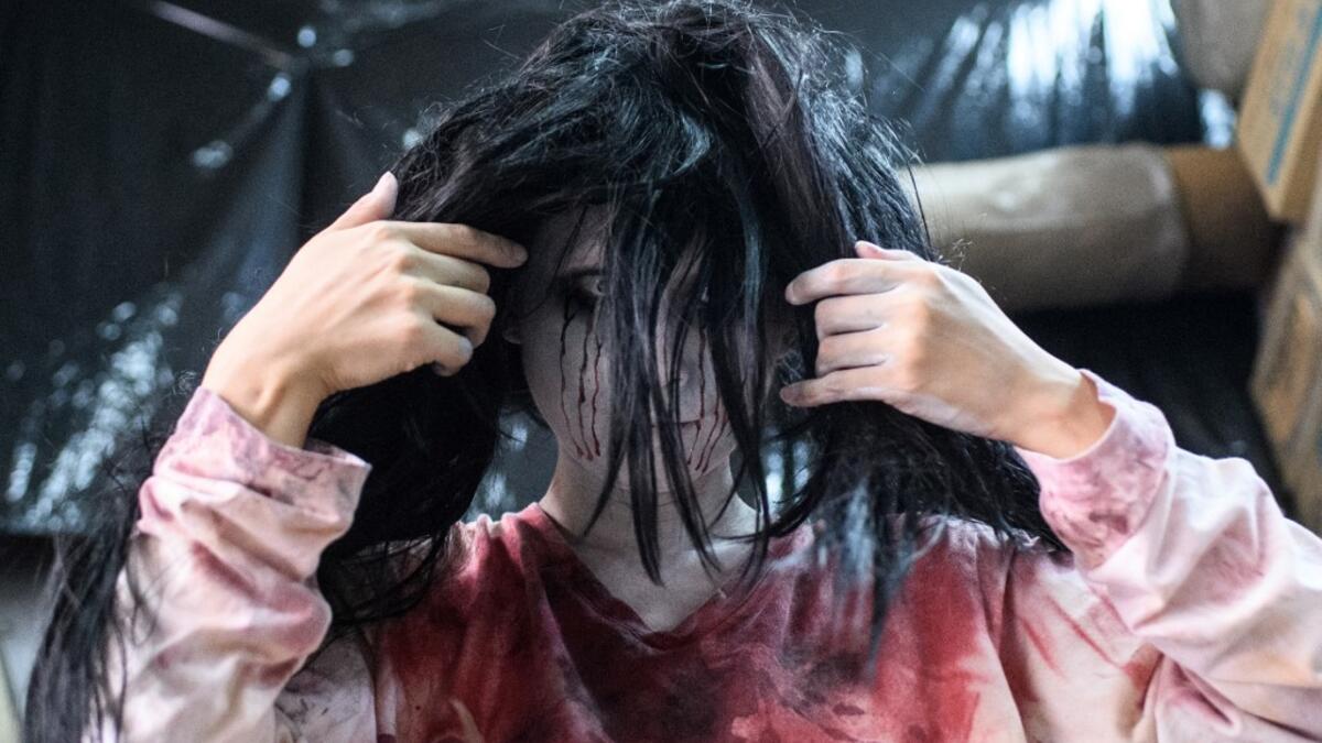 This picture taken on June 15, 2020 shows actress Ayaka Imaide, 34, putting on zombie makeup before a demonstration of a drive-in haunted house at a garage in Tokyo. A car horn beeps and the horror begins: a bloody murder and rampaging zombies. But this drive-in haunted house in Japan protects against the most terrifying enemy of all -- coronavirus. Inside a car, guests can scream as loudly as they like, with no mask required, as hideous creatures daubed in blood swarm towards them.  Philip FONG / AFP