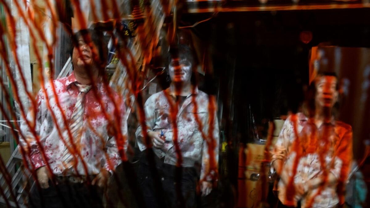 This picture taken on June 15, 2020 shows fake blood on the window of a car as actors (L-R) Kota Hanegawa, 28, Kenta Iwana, 25, and Asami Takeuchi, 33, rest after a demonstration of a drive-in haunted house at a garage in Tokyo. Philip FONG / AFP