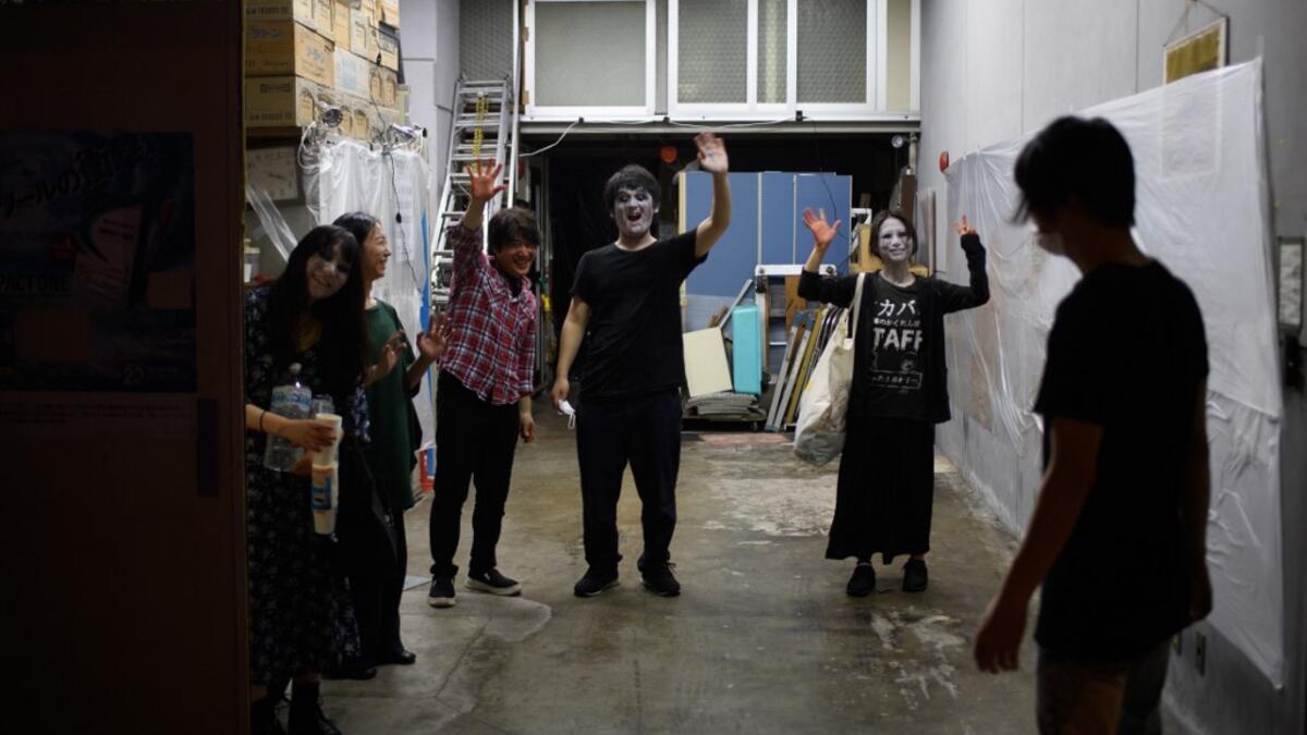This picture taken on June 15, 2020 shows drive-in haunted house actors (L to R) Haruna Suzuki, 20, Asami Takeuchi, 33, Kota Hanegawa, 28, Kenta Iwana, 25, Ayaka Imaide, 34, and sound and lights engineer Daichi Ono waing to AFP reporters after a demonstration of a drive-in haunted house at a garage in Tokyo. A car horn beeps and the horror begins: a bloody murder and rampaging zombies.Philip FONG / AFP