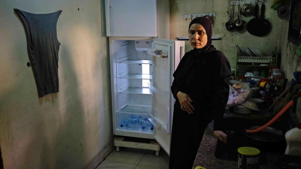 A Lebanese woman stands next to her empty refrigerator in her apartment in the port city of Tripoli north of Beirut on June 17, 2020. Lebanon's economic crisis has led to a collapse of the local currency and purchasing power, plunging whole segments of the population into poverty as exemplified by near-empty fridges in many households. IBRAHIM CHALHOUB / AFP