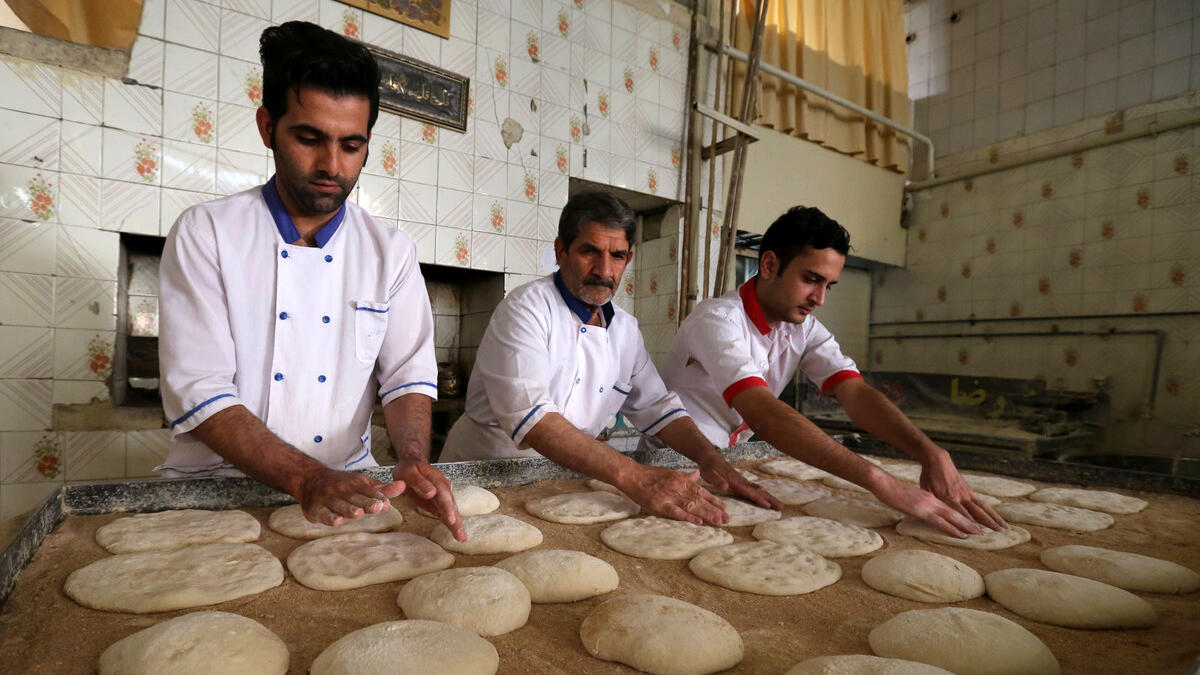 Iranian bakers Farzad Rabiei (L), 30, Esmail Asghari, 66, and Mojtaba Haydari, 23, prepare dough for Barbari bread in Tehran on June 7, 2020. ATTA KENARE / AFP