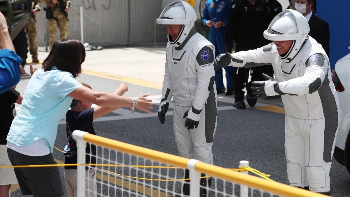 NASA astronauts Bob Behnken (R) and Doug Hurley say goodbye to family members after walk ing out of the Operations and Checkout Building on their way to the SpaceX Falcon 9 rocket with the Crew Dragon spacecraft on launch pad 39A at the Kennedy Space Center on May 30, 2020 in Cape Canaveral, Florida. The inaugural flight will be the first manned mission since the end of the Space Shuttle program in 2011 to be launched into space from the United States. Joe Raedle/Getty Images/AFP