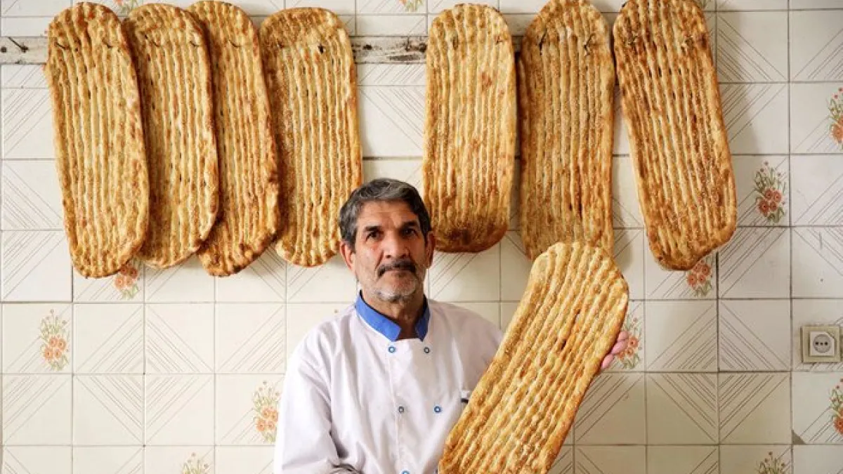 Iranian baker Esmail Asghari, 66, poses with Barbari bread in Tehran on June 7, 2020. ATTA KENARE / AFP