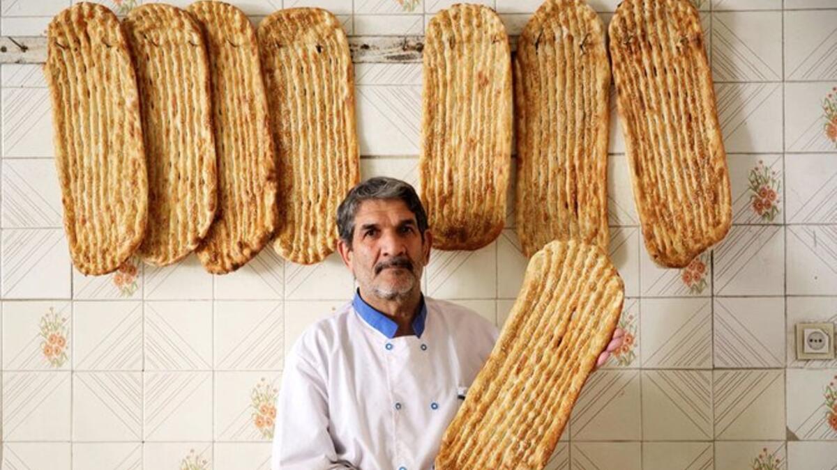 Iranian baker Esmail Asghari, 66, poses with Barbari bread in Tehran on June 7, 2020. ATTA KENARE / AFP