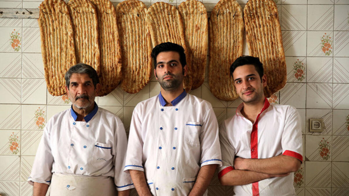 Iranian bakers Esmail Asghari, 66, Farzad Rabiei, 30, and Mojtaba Haydari, 23, pose with Barbari bread in Tehran on June 7, 2020. ATTA KENARE / AFP