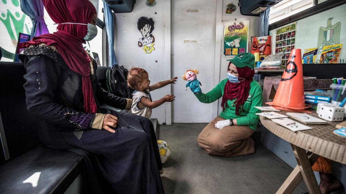 A woman looks on as a worker entertains a homeless child inside one of the mobile units run by the Egyptian authorities and used as part of the "Atfal bala ma'wa" (Children without a home) social program, in the capital Cairo's Abbasia district on June 22, 2020. Khaled DESOUKI / AFP