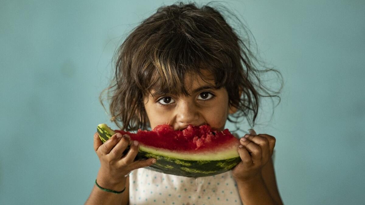 A girl eats a watermelon slice while at a school building where Syrians -- displaced from the area of Ras al-Ain by the Turkish offensive on the northeast -- are staying in the city of Hasakah, on June 30, 2020. Delil SOULEIMAN / AFP