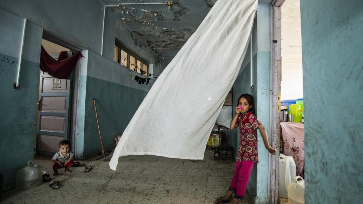 A girl looks on while standing by a doorway at the hallway of a school building where Syrians -- displaced from the area of Ras al-Ain by the Turkish offensive on the northeast -- are staying in the city of Hasakah, on June 30, 2020. Delil SOULEIMAN / AFP