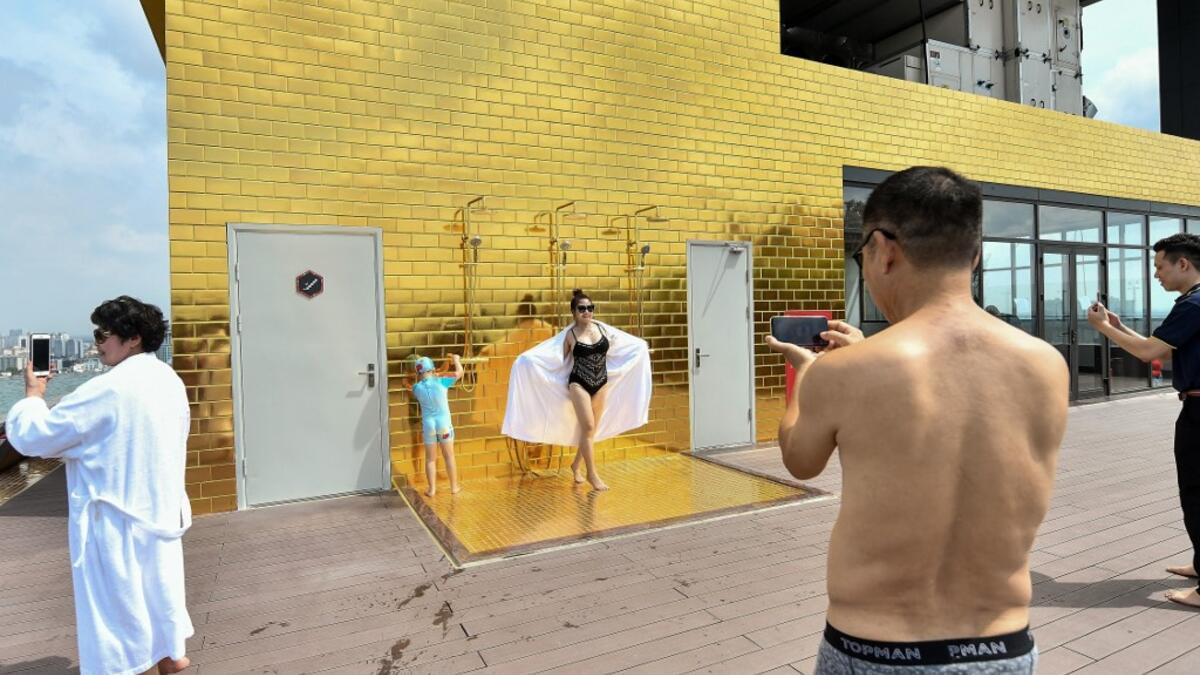 Guests pose for photographs at the infinity pool of the newly-inaugurated Dolce Hanoi Golden Lake hotel, the world's first gold-plated hotel, in Hanoi on July 2, 2020. Manan VATSYAYANA / AFP