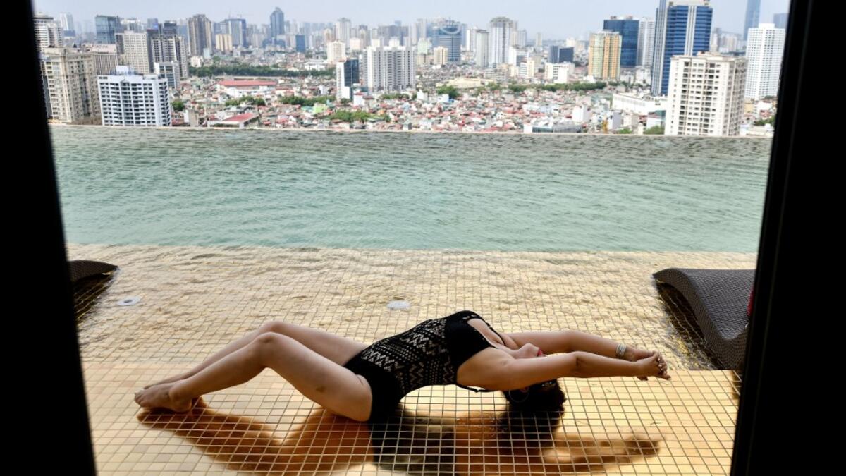 A guest poses for photographs at the infinity pool of the newly-inaugurated Dolce Hanoi Golden Lake hotel, the world's first gold-plated hotel, in Hanoi on July 2, 2020. Manan VATSYAYANA / AFP