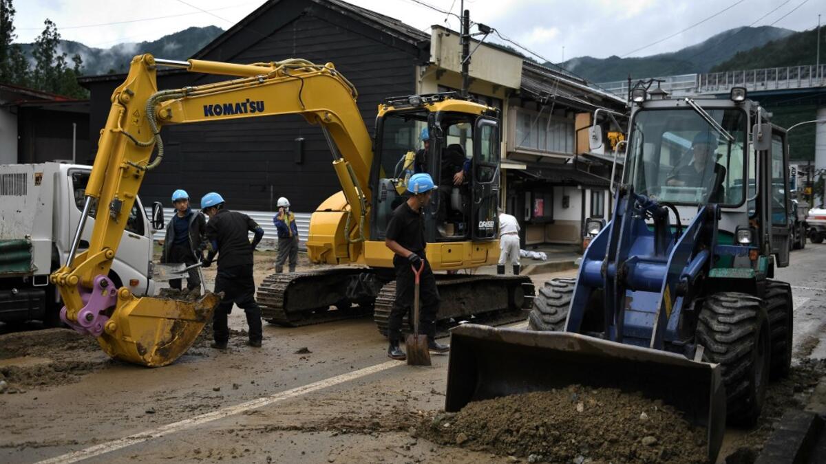 Workers clear debris and mud outside homes following heavy rains and flooding in the village of Gero, Gifu prefecture on July 9, 2020. Japanese emergency services and troops were scrambling to reach thousands of homes cut off by devastating flooding and landslides that have killed dozens and caused widespread damage. Philip FONG / AFP