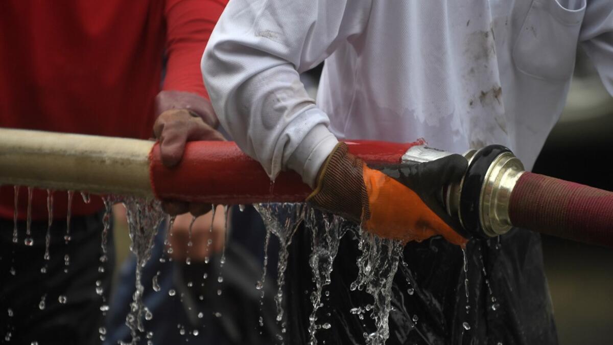 People clear debris and mud outside homes following heavy rains and flooding in the village of Gero, Gifu prefecture on July 9, 2020. Japanese emergency services and troops were scrambling to reach thousands of homes cut off by devastating flooding and landslides that have killed dozens and caused widespread damage. Philip FONG / AFP