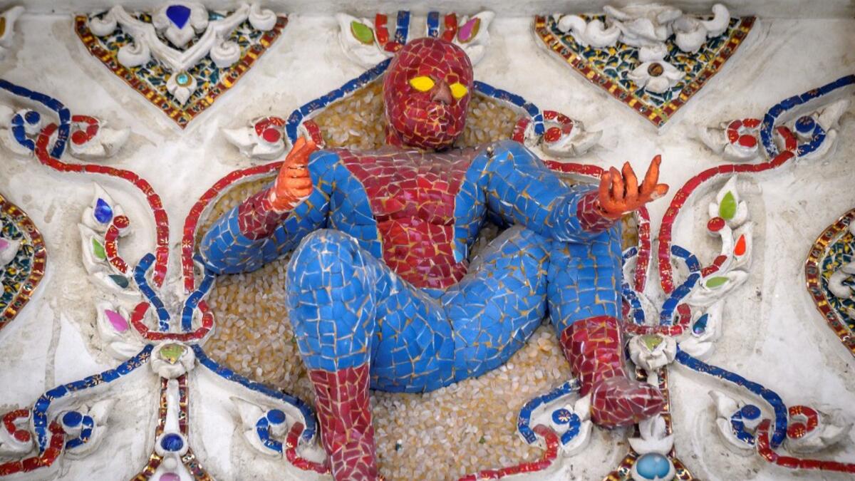 This photograph taken on July 14, 2020 shows a figure of Spiderman on the facade of the Wat Pariwat Buddhist temple in Bangkok. Wat Pariwat, also known as "the David Beckham Temple", is decorated with statues of superheroes and comic characters as well as mythical and imaginary creatures. A golden-plated sculpture of the English football player holding the base of a Buddha statue in one of the buildings gives the temple its nickname. Mladen ANTONOV / AFP