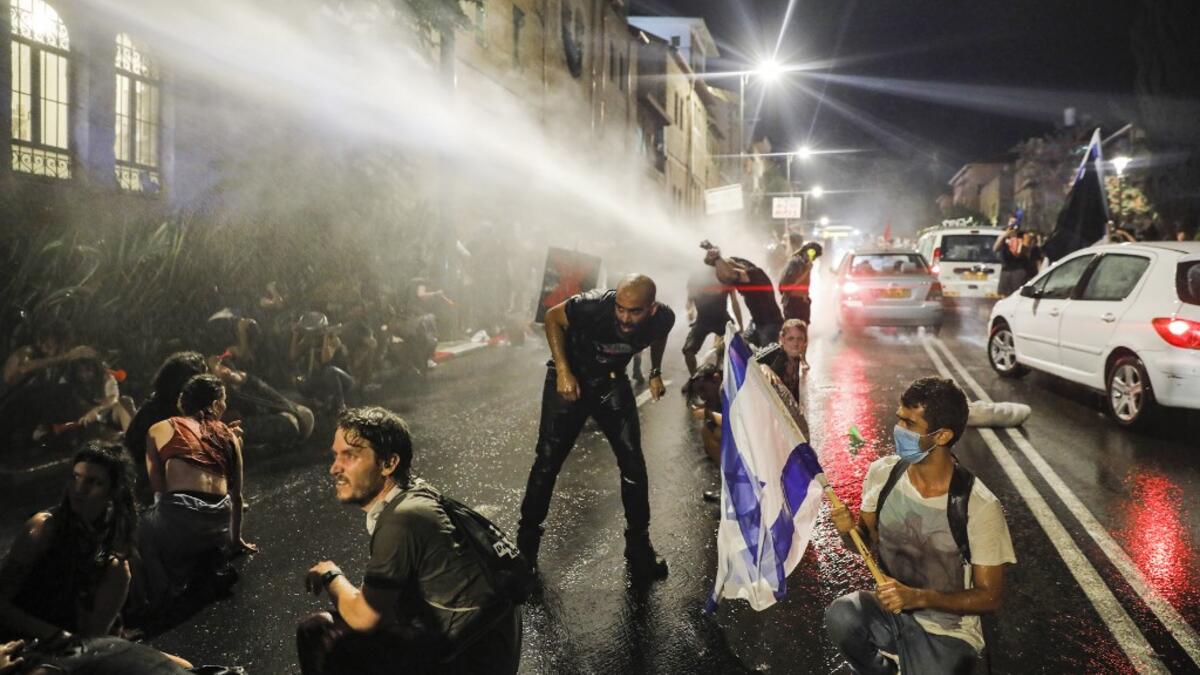 Israeli police spray protesters (clad in masks due to the COVID-19 coronavirus pandemic) with water cannon during an anti-government demonstration in Jerusalem, on July 18, 2020. Ahmad GHARABLI / AFP