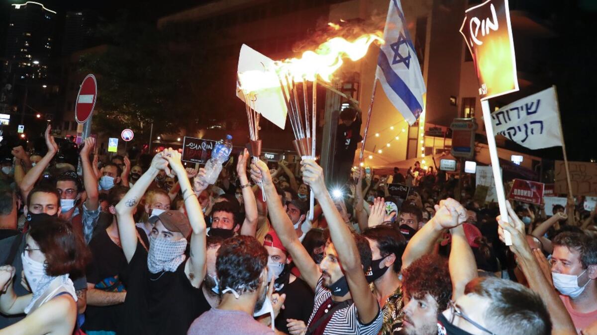 Israelis wearing protective face masks due to the COVID-19 coronavirus pandemic, take part in a demonstration on July 18, 2020, in Charles Clore Park in the Israeli coastal city of Tel Aviv to protest against the Israeli government and Prime Minister Benjamin Netanyahu for the broken promises made by the Israeli government during the Covid-19 pandemic. Israel's government said today it was imposing new restrictions to limit the spiraling spread of coronavirus.