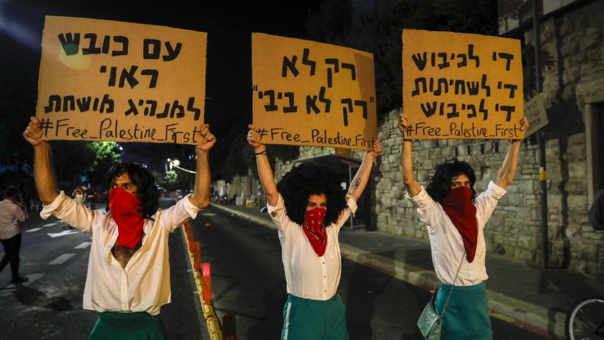Israeli demonstrators lift placards during a rally against Prime Minister Benjamin Netanyahu outside his official residence in Jerusalem, on July 18, 2020, amid the coronavirus pandemic. Israeli police fired water cannons to disperse anti-government protests attended by thousands on Saturday, as public anger mounts over the handling of the coronavirus crisis.