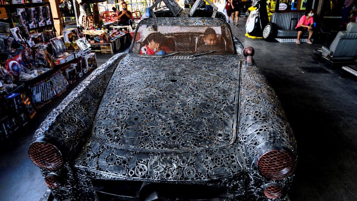 This photograph taken on July 18, 2020 shows children playing in a car made of scrap metal parts at the Ban Hun Lek museum in Ang Thong, some 100km north of Bangkok. "Ban Hun Lek" or "The House of Steel Robots" is a museum where a collective of artists display their scrap metal creations depicting popular comics and sci-fi film characters. Mladen ANTONOV / AFP