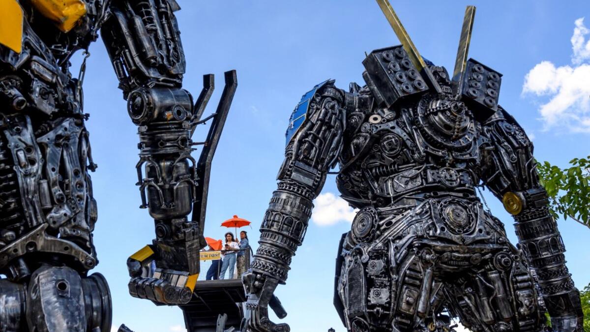 This photograph taken on July 18, 2020 shows tourists taking photos of life-sized sculptures of characters from the "Transformers" film franchise made of scrap metal parts at the Ban Hun Lek museum in Ang Thong, some 100km north of Bangkok. "Ban Hun Lek" or "The House of Steel Robots" is a museum where a collective of artists display their scrap metal creations depicting popular comics and sci-fi film characters. Mladen ANTONOV / AFP