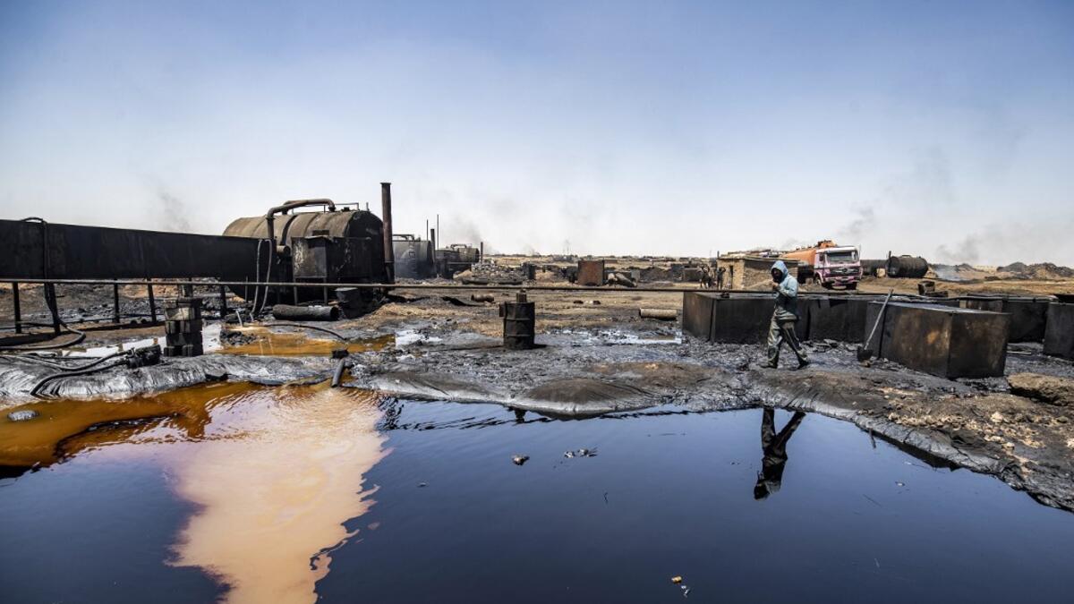 A man walks at a makeshift refinery using burners to distill crude oil in the village of Bishiriya in the countryside near the town of Qahtaniya west of Rumaylan (Rmeilan) in Syria's Kurdish-controlled northeastern Hasakeh province, on July 19, 2020. DELIL SOULEIMAN / AFP