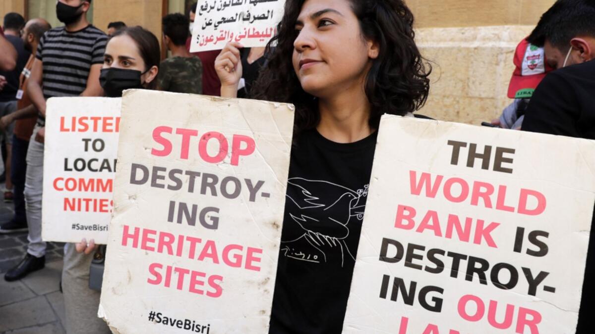 Demonstrators hold placards in front of the World Bank offices in the downtown district of the capital Beirut on July 25, 2020, as they protest against the Bisri dam project, partly financed by the World Bank. The government says the Bisri dam is vital to tackling chronic water shortages. But activists say it will ravage most of the region's farmland and historic sites, and they also fear the consequences of building it on a seismic fault line.  ANWAR AMRO / AFP