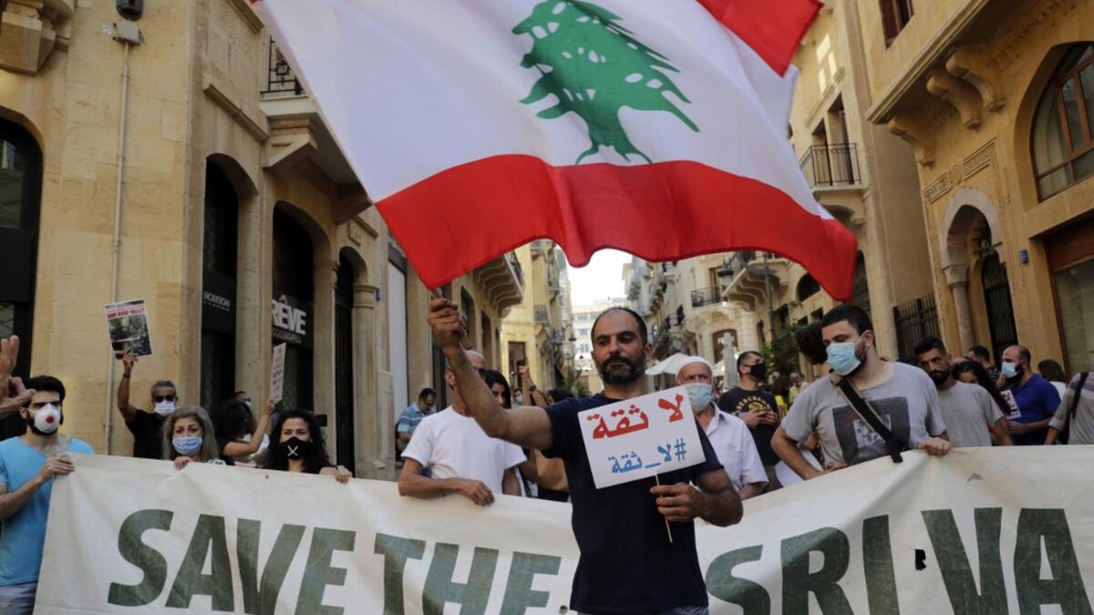 A man waves a large Lebanese national flag as he takes part in a protest in front of the World Bank offices in the downtown district of the capital Beirut on July 25, 2020, against the Bisri dam project, partly financed by the World Bank. The government says the Bisri dam is vital to tackling chronic water shortages. But activists say it will ravage most of the region's farmland and historic sites, and they also fear the consequences of building it on a seismic fault line.  ANWAR AMRO / AFP