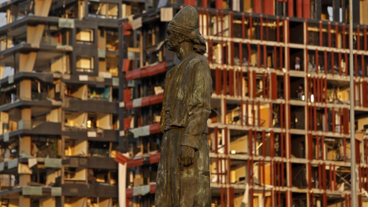 The statue of the Lebanese Emigrant stands intact in front of damaged buildings at the entrance of Beirut's port following a powerful explosion in its vicinity in Lebanon's capital on August 4, 2020. Marwan TAHTAH / AFP