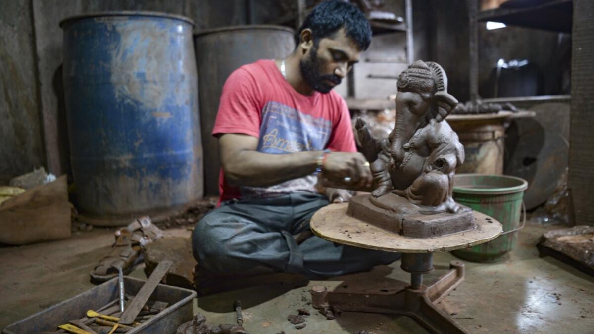 In this picture taken on August 11, 2020, an artisan prepares a clay idol of elephant headed Hindu god Ganesha at Muslim potter Yusuf Zakaria Galwani's workshop at Kumbharwada inside the Dharavi slums in Mumbai. After the coronavirus pandemic clobbered his pottery business, a Muslim artisan from India's largest slum turned to a Hindu god to revive his fortunes by making environmentally-friendly Ganesha idols for an upcoming festival. In Mumbai's Dharavi slum, Galwani worked alongside his two brothers to cre