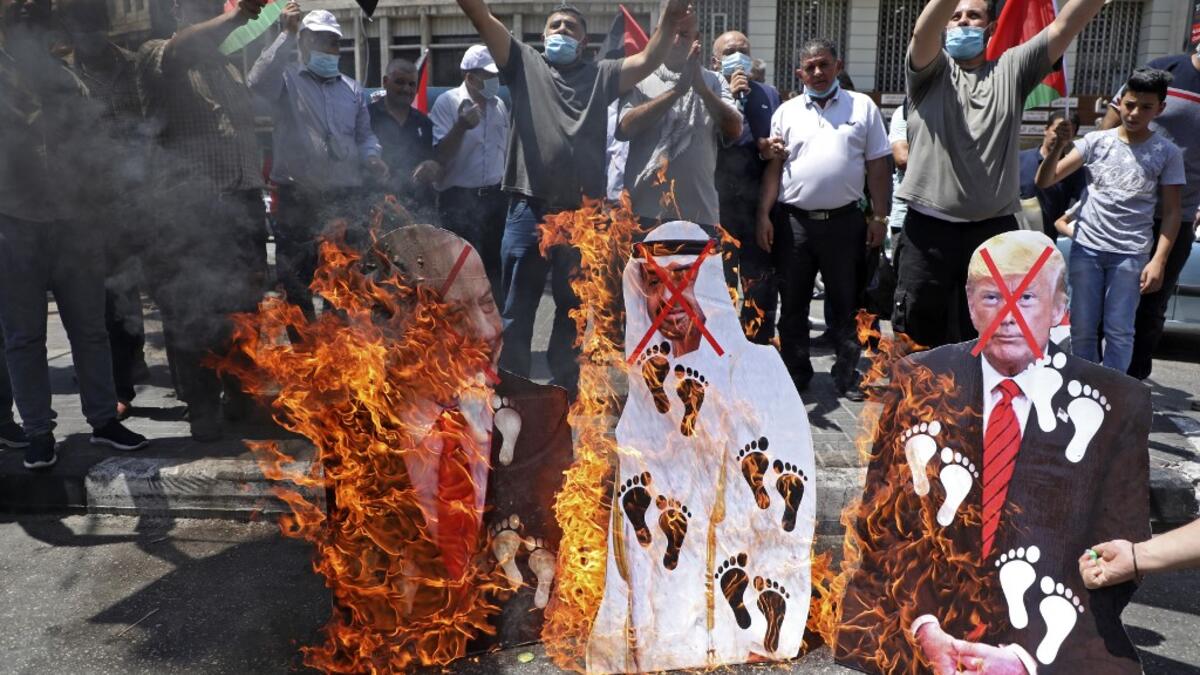 Palestinian protesters set aflame cut-outs showing the faces of (L to R) Israeli Prime Minister Benjamin Netanyahu, Abu Dhabi Crown Prince Sheikh Mohammed bin Zayed al-Nahyan, and US President Donald Trump, during a demonstration in Nablus in the occupied West Bank on August 14, 2020 against a US-brokered deal between Israel and the UAE. AFP