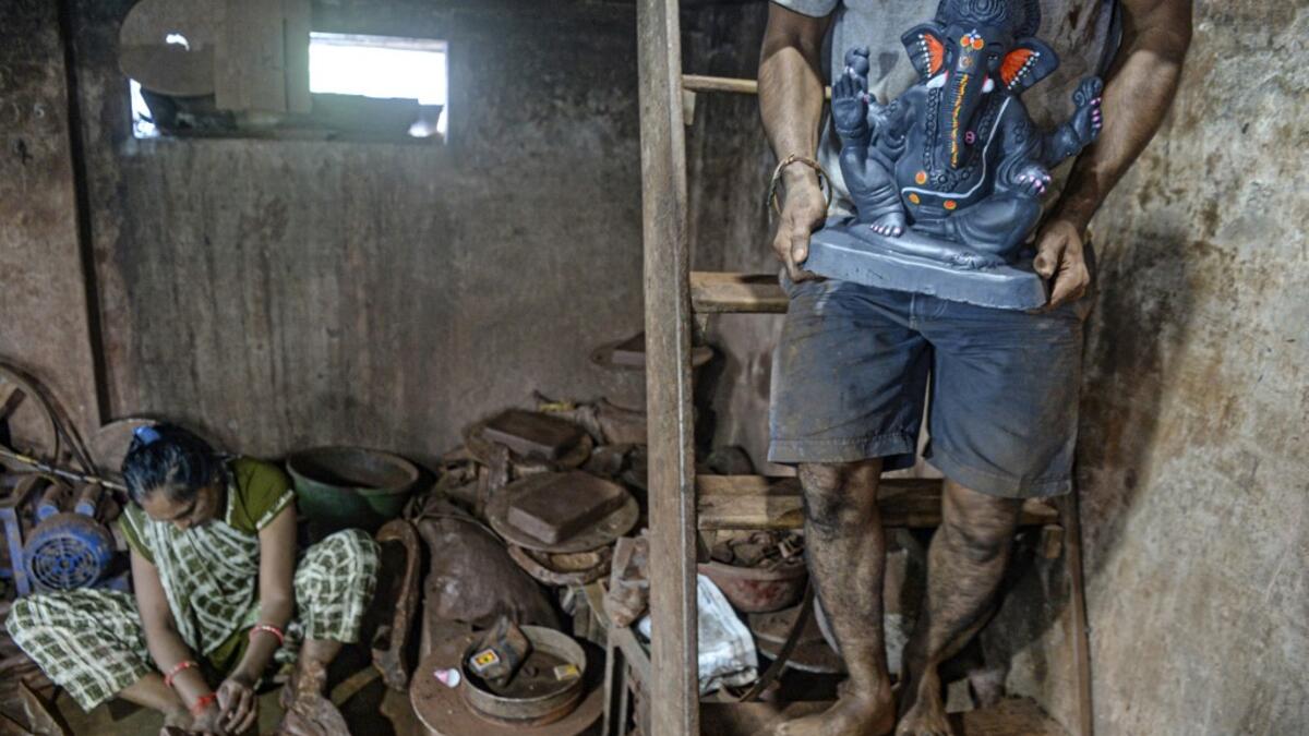 In this picture taken on August 15, 2020, an artisan carries a clay idol of elephant headed Hindu god Ganesha at Muslim potter Yusuf Zakaria Galwani's workshop at Kumbharwada inside the Dharavi slums in Mumbai. After the coronavirus pandemic clobbered his pottery business, a Muslim artisan from India's largest slum turned to a Hindu god to revive his fortunes by making environmentally-friendly Ganesha idols for an upcoming festival. In Mumbai's Dharavi slum, Galwani worked alongside his two brothers to crea