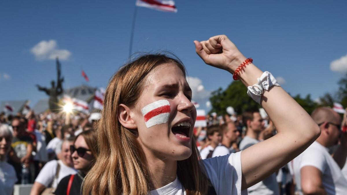 A woman Belarus opposition supporter with a drawing of a former white-red-white flag of Belarus used in opposition to the government punches the air during a demonstration in central Minsk on August 16, 2020. The Belarusian strongman, who has ruled his ex-Soviet country with an iron grip since 1994, is under increasing pressure from the streets and abroad over his claim to have won re-election on August 9, with 80 percent of the vote. Sergei GAPON / AFP