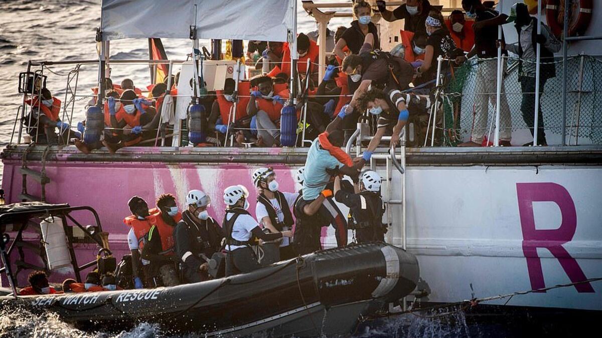 Crew members of civil sea rescue ship Sea-Watch 4 and medical Doctors Without Borders (MSF) on inflatable boats help migrants to get off the rescue ship (AFP)