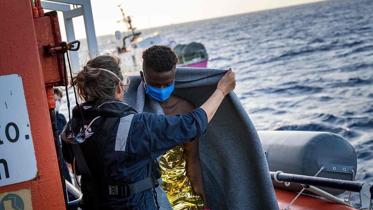 Civil sea rescue ship Sea-Watch 4 crew and Doctors without Borders members help migrants and cover them with blankets  (AFP)