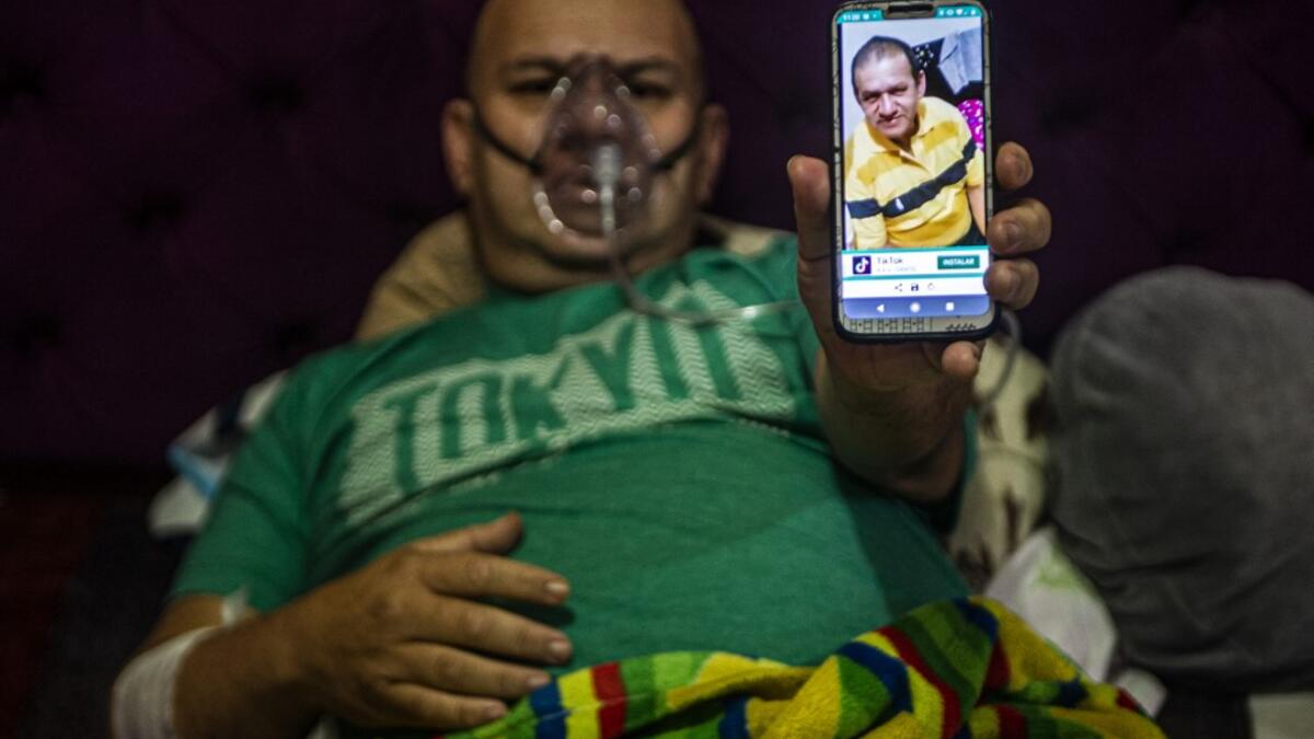 Venezuelan Wilmer Hernandez, 44, shows a picture of his father Wilmer Arcadio Hernandez, 63, as he remains connected to an oxygen tank in his home in Villa Maria del Triunfo, south of Lima, Peru, on June 25, 2020. Global deaths from the coronavirus have almost reached on September 25, 2020 the grim threshold of one million. Around one-third of fatalities were in Latin America, where countries with overstretched medical resources are preparing for a further onslaught. ERNESTO BENAVIDES / AFP