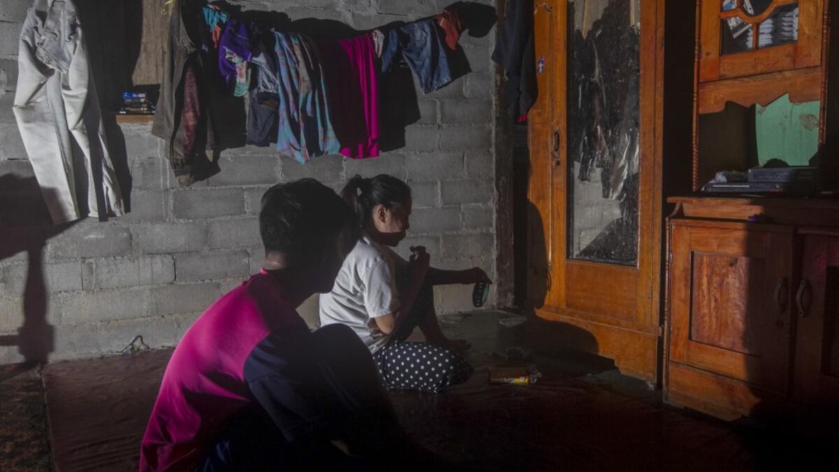 This picture taken on July 22, 2020 shows Marsuki (L) with his underage wife Imani (not her real name) watching television at their parent's house in the village of Pokkang in Mamuju, West Sulawesi. Child marriage has long been common in traditional communities from the Indonesian archipelago to India, Pakistan and Vietnam, but numbers had been decreasing as charities made inroads by encouraging access to education and women's health services. YUSUF WAHIL / AFP