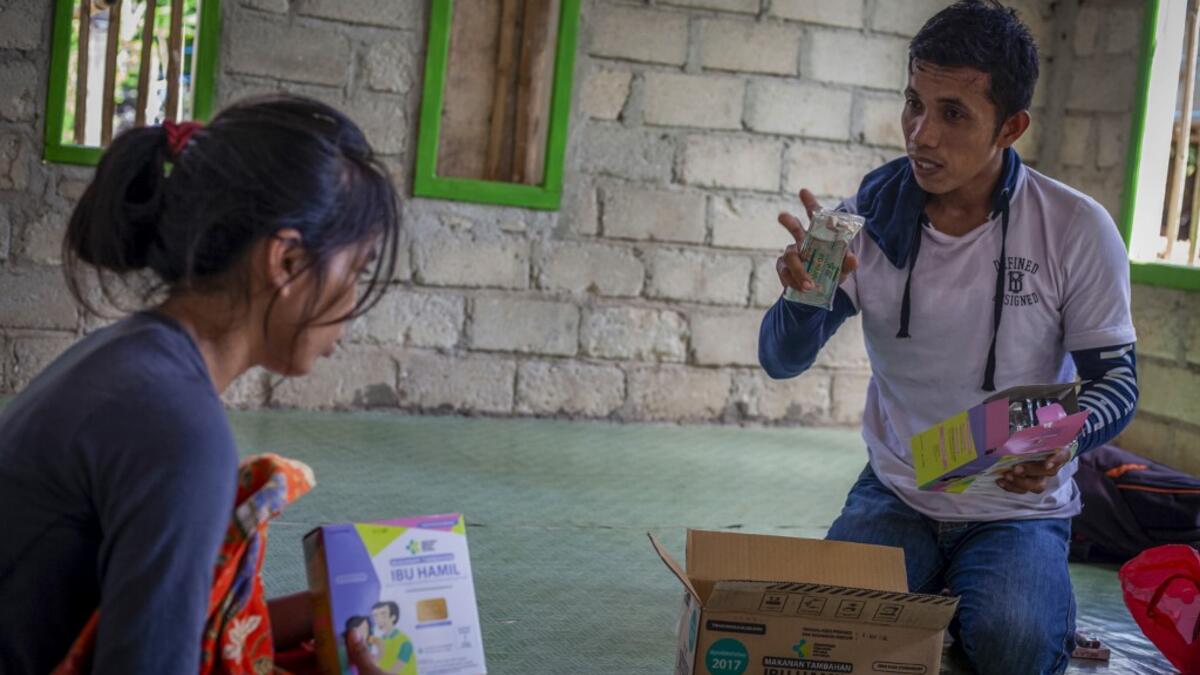 This picture taken on February 11, 2019 shows Ninda (L), who is two months pregnant and married, listening to directions from a health worker at her home in the village of Pulau Karampuang in Mamuju, West Sulawesi. Child marriage has long been common in traditional communities from the Indonesian archipelago to India, Pakistan and Vietnam, but numbers had been decreasing as charities made inroads by encouraging access to education and women's health services. YUSUF WAHIL / AFP