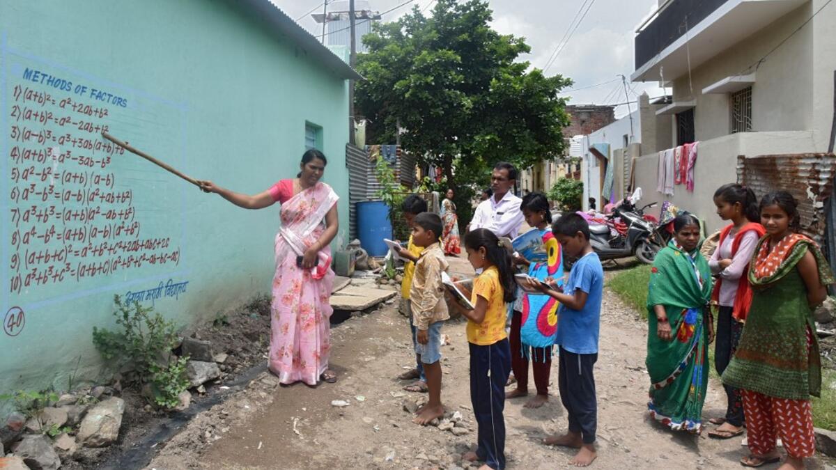 Half a dozen children in an Indian village gather around their teacher as she points a stick at a lesson painted on a wall, one of many which are part of an unusual effort to help poor students keep up with their education amid the coronavirus pandemic. AFP