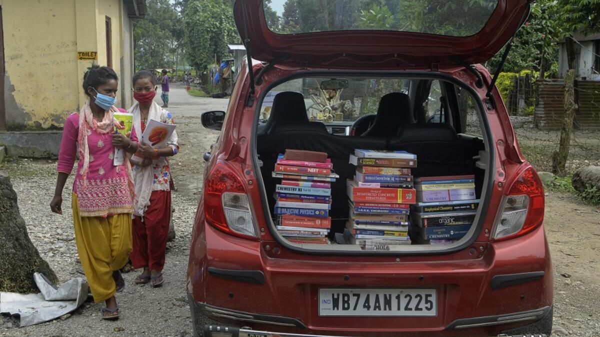 Youths from Merry view Tea Garden organisation walk near a book library car to attend a class as part of 'Tuition for Rs 10' project, origanized by Indian couple Anirban Nandy and Poulami Chaki Nandy for underprivileged students unable to assist online classes at Hatighisa village, some 26 km from Siliguri, on September 1, 2020, as schools remain closed due the Covid-19 coronavirus pandemic. DIPTENDU DUTTA / AFP