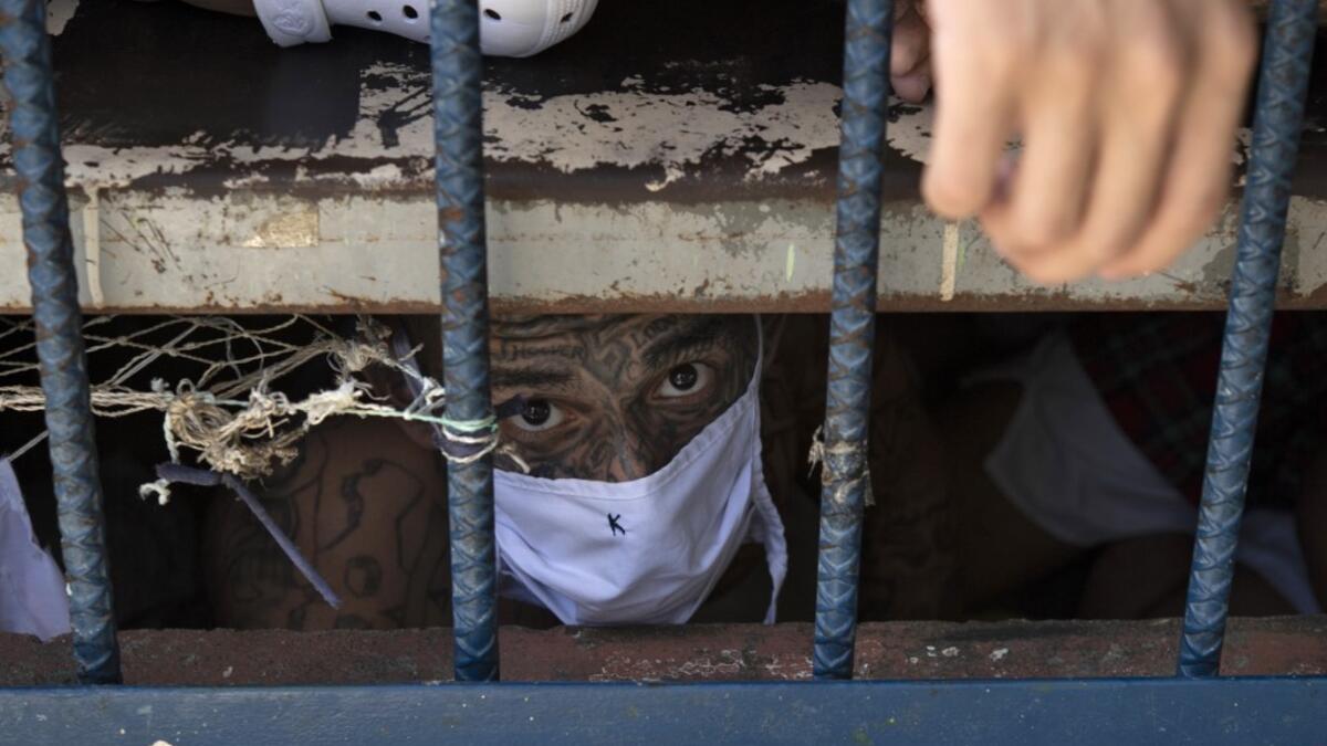 A member of the 18 gang looks on from an overcrowded cell at the Quezaltepeque prison, in Quezaltepeque, El Salvador, on September 4, 2020. Authorities from the General Directorate of Penal Centres (DGCP) visited three Salvadorean prisons, some of maximum security, to check the situation of inmates and carry out searches amid the COVID-19 novel coronavirus pandemic. Yuri CORTEZ / AFP