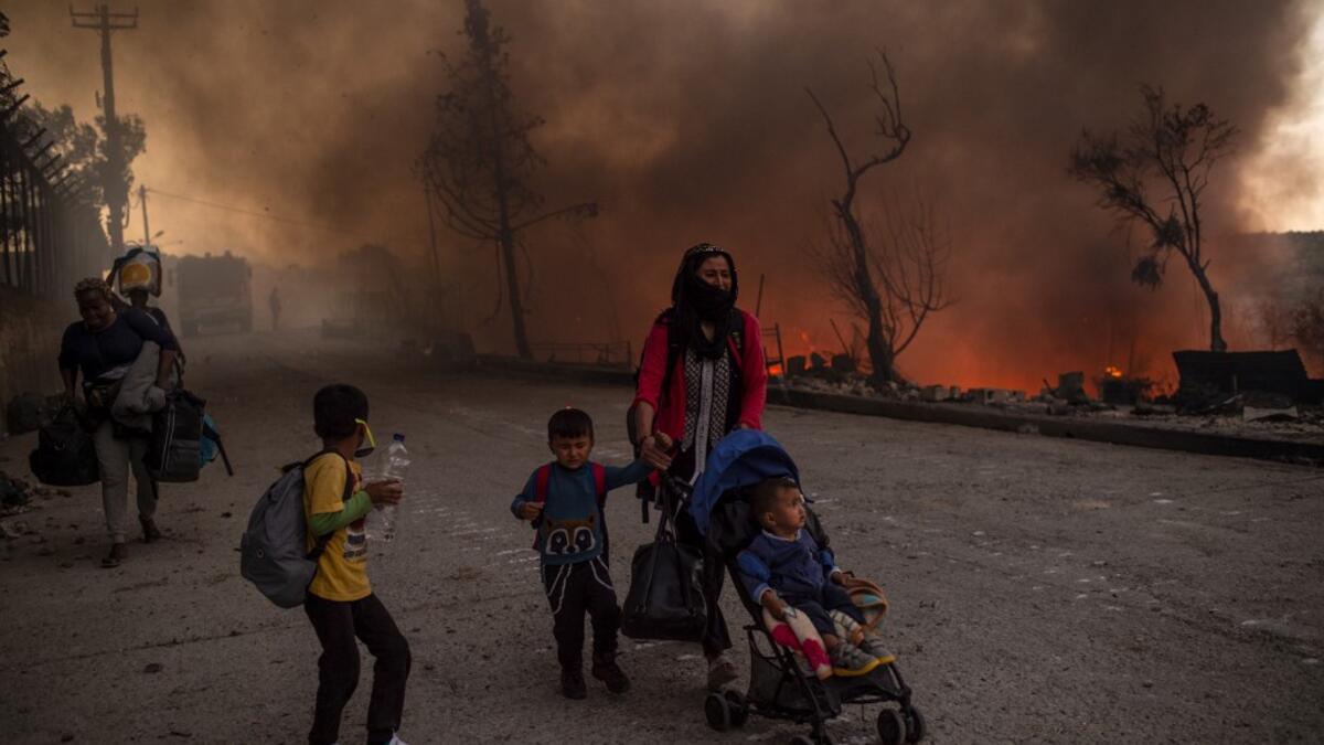 A woman and children flee flames major fire broke out in the Moria migrants camp on the Greek Aegean island of Lesbos, on September 9, 2020.