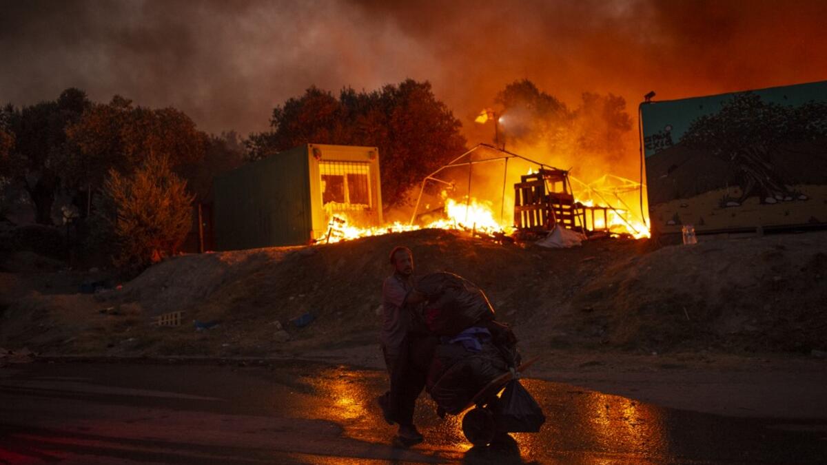 A man carrying belongings flees flames after a major fire broke out in the Moria migrants camp on the Greek Aegean island of Lesbos, on September 9, 2020.