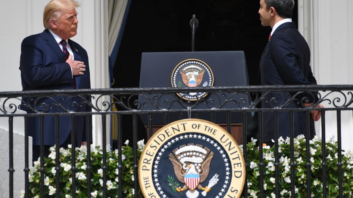 US President Donald Trump puts his hand over his heart as UAE Foreign Minister Abdullah bin Zayed Al-Nahyan (R) speaks from the Truman Balcony at the White House during the signing ceremony of the Abraham Accords where the countries of Bahrain and the United Arab Emirates recognize Israel, on the South Lawn of the White House in Washington, DC, September 15, 2020.