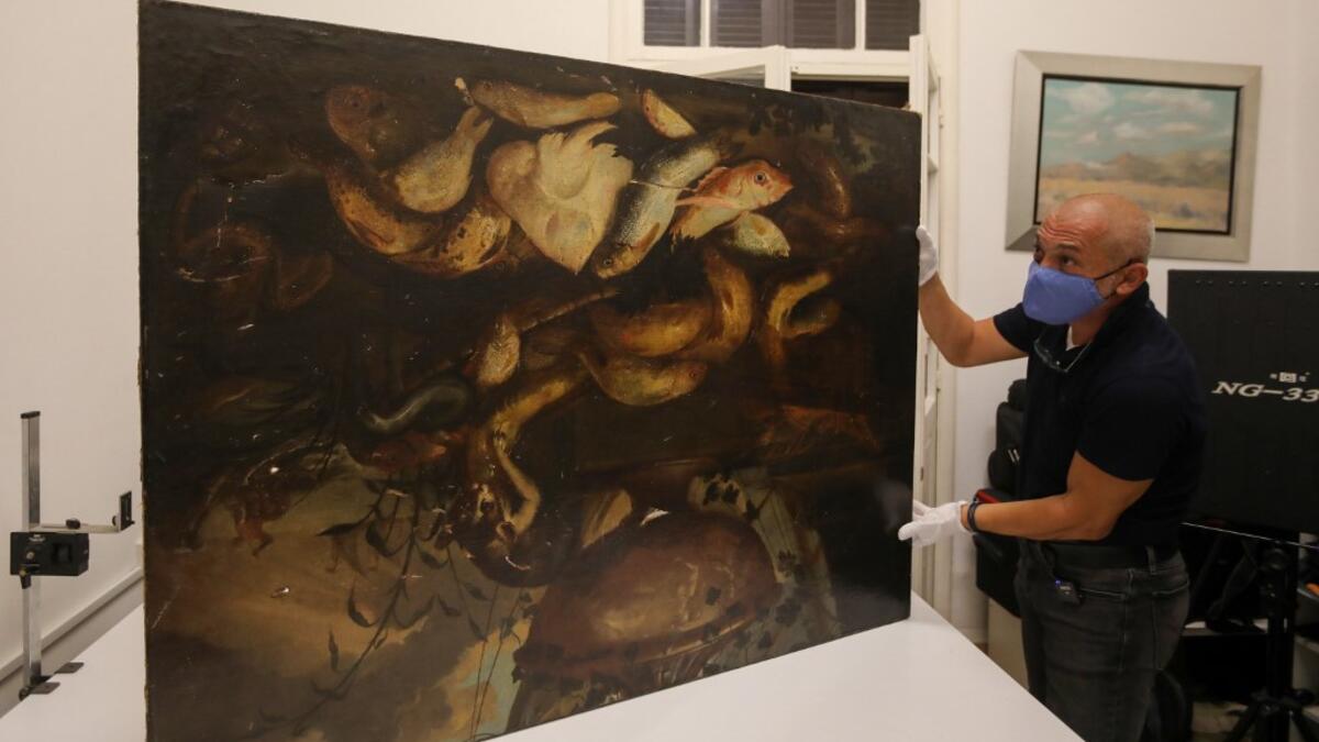 Gaby Maamary, a Lebanese artwork conservation specialist, examines a 17th-century painting by Italian painter Elena Recco, damaged in the Beirut port blast, at his studio in the capital Beirut on September 17, 2020. ANWAR AMRO / AFP