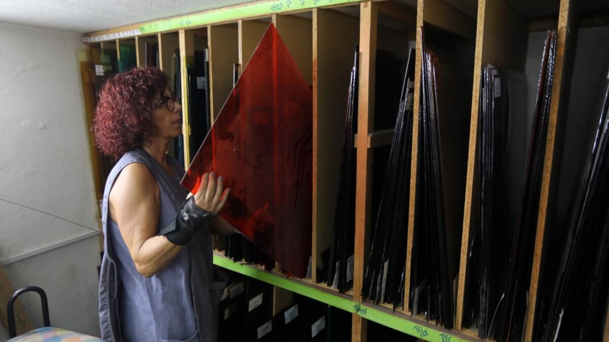 Lebanese stained glass artist Maya Husseini, 60, chooses red glass to be used on one of her works in progress, in her basement workshop on the outskirts of the capital Beirut, on September 18, 2020. ANWAR AMRO / AFP
